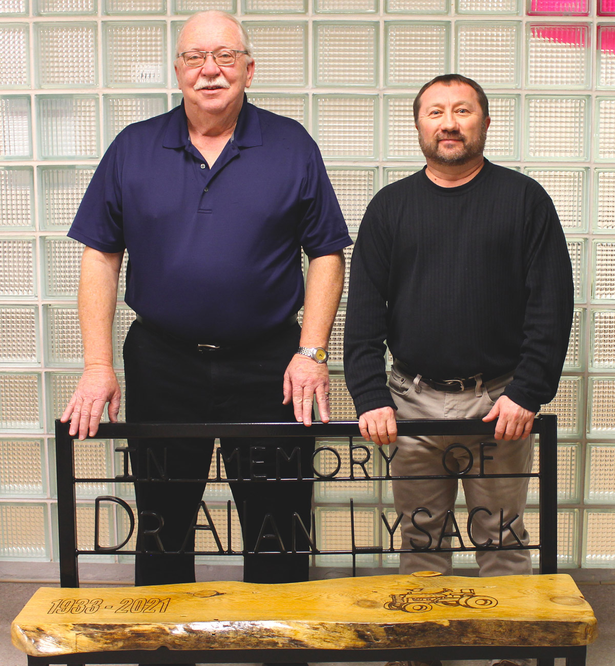 From left, Foundation Chair Greg Thompson and Public Relations Director Blaine Kraushaar stand in front of a bench donated by the Lysack family in memory of Dr. Allan Lysack.